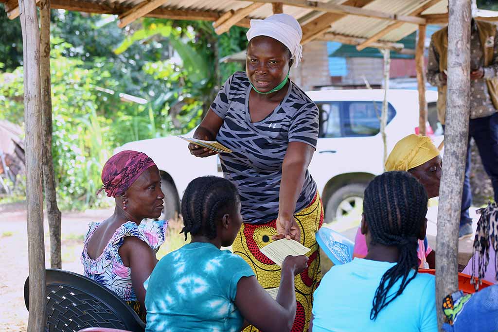 Margaret Bouibo delar ut böcker under en workshop. Den ensamstående mamman med tio barn har tagit en ledande ställning i sitt samhälle i Buchanan, Grand Basso County, i Liberia. Foto: Wolobah Sali. 
